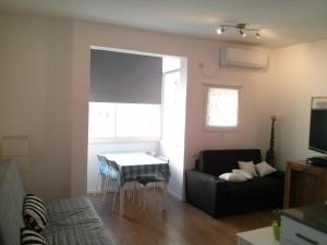 a living room with a black couch and a table at Haatzmaut Bat Yam Beach in Bat Yam