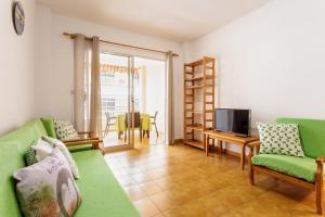 Una sala de estar con un sofá verde y un televisor. en Vivienda Vacacional El Faro, en Puerto Naos, en Los Llanos de Aridane