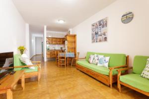Una sala de estar con sofás verdes y una mesa. en Vivienda Vacacional El Faro, en Puerto Naos, en Los Llanos de Aridane