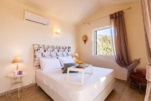 Un pequeño dormitorio con una cama blanca y una ventana en Villas Muscalas by Konnect, 200m from the Beach en Lákka