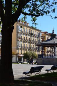 two park benches in front of a large building at Plaza Pombo B&B - Hostal in Santander