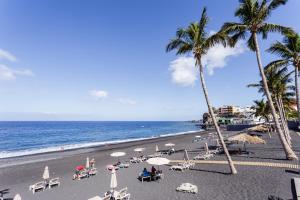Una playa con palmeras y sillas y el océano. en Vivienda Vacacional El Faro, en Puerto Naos, en Los Llanos de Aridane