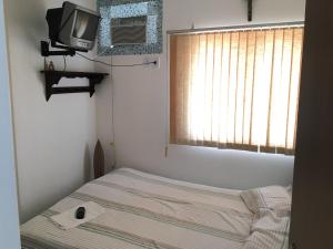 a small bedroom with a bed and a television at Flat em Sao Jose da Coroa Grande in São José da Coroa Grande