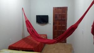 uma rede vermelha num quarto com televisão em Beach House em Flecheiras