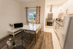 a kitchen with a table, chairs and a refrigerator at Meridian Apartment Suites in Southend-on-Sea