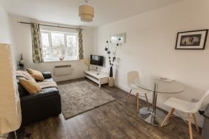 un soggiorno con divano e tavolo in vetro di Meridian Apartment Suites a Southend-on-Sea