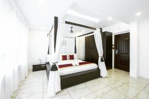 a bedroom with a canopy bed with white curtains at Rahul Residency in Mangalore