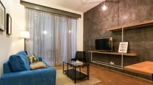 ein Wohnzimmer mit einem blauen Sofa und einem TV in der Unterkunft Valletta collection - Mint Suite in Valletta