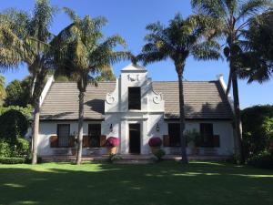 a white house with palm trees in the yard at The White Manor in Cape Town