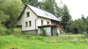 a white house on a hill in a field at chalupa Krkonoše in Háje