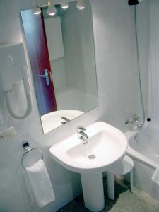 Baño blanco con lavabo y espejo en Hotel Bahía Bayona, en Baiona