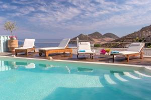 a group of chairs sitting on a deck next to a swimming pool at Theologos Houses in Grikos