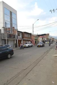 uma movimentada rua da cidade com carros e pessoas em motocicletas em Hotel H21 em Cali