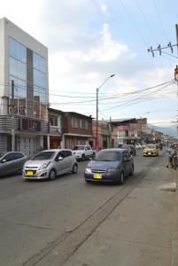 eine Gruppe von Autos, die eine Stadtstraße hinunterfahren in der Unterkunft Hotel H21 in Cali