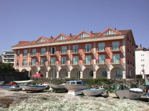a large building with a boat parked in front of it at Hotel Bahía Bayona in Baiona