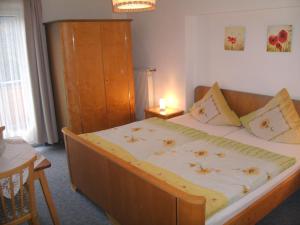 Schlafzimmer mit einem großen Bett mit einem Kopfteil aus Holz in der Unterkunft Pension Reindlhöh in Lohberg