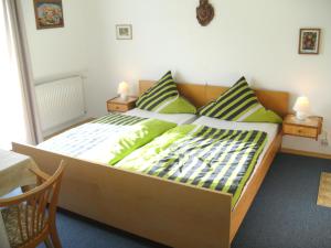 ein Schlafzimmer mit einem großen Bett mit grüner Bettwäsche und Kissen in der Unterkunft Pension Reindlhöh in Lohberg