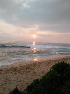 Bandula's Beach Inn في هيكادوا: غروب الشمس على الشاطئ مع المحيط