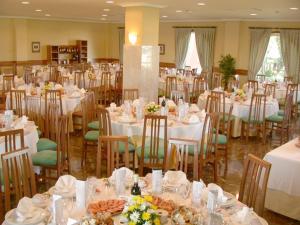 un comedor lleno de mesas y sillas con manteles blancos en Hotel Bahía Bayona, en Baiona
