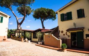 dom z zielonymi okiennicami i drzewami w tle w obiekcie Locanda Di Ansedonia - Ristorante GRIGL"io" w mieście Orbetello