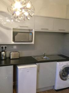 a kitchen with white cabinets and a sink and a microwave at Modern Luxury Central Apartment in Birmingham