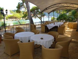 een restaurant met witte tafels en stoelen en het water bij Hotel Solitudo in Ubli