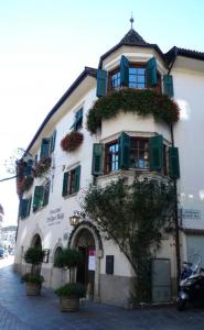 a white building with green shutters and plants on it at Weißes Rössl in Appiano sulla Strada del Vino