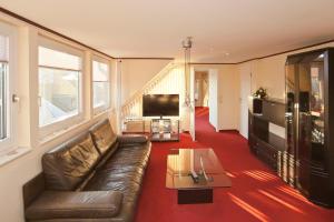 a living room with a leather couch and a tv at Ferienwohnung Geestemuende in Bremerhaven