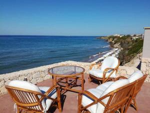 a group of chairs and tables on a balcony overlooking the ocean at Dip in the blue - 2 in Agios Georgios