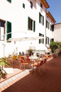 un patio al aire libre con mesas, sillas y una sombrilla en Hotel Savoia e Campana, en Montecatini Terme