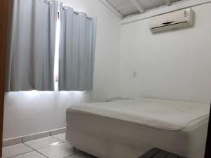a white room with a bed and a window at Pousada Residencial Família Dragone in Bombinhas