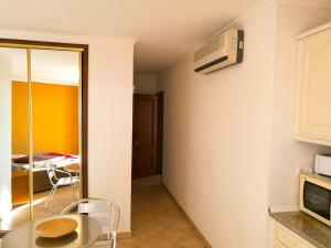 Porto Mos Residence في لاغوس: غرفة مع طاولة وميكروويف على الحائط