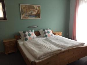 Schlafzimmer mit einem Bett mit weißer Bettwäsche und Kissen in der Unterkunft Gästehaus Wagner in Grainau