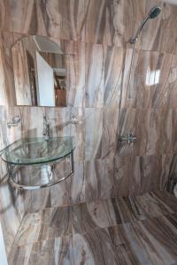 ドブリニシュテにあるOasis Guest Houseのバスルーム(ガラスの洗面台、シャワー付)