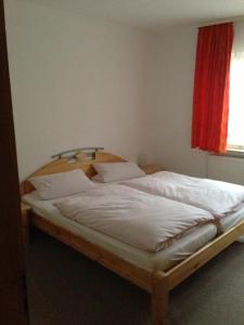 Cama grande en habitación con ventana roja en Pension Freund, en Rothenburg ob der Tauber