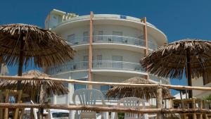 a building with chairs and umbrellas in front of it at Hotel Il Girasole in Bova Marina