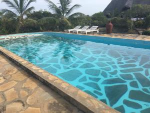 a large swimming pool with chairs in a resort at Red Sunshine Villa Mayungu to Watamu Your Tropical Dream in Malindi
