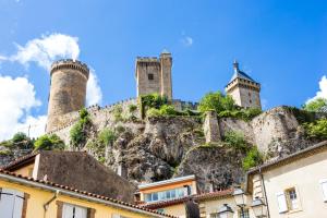 un castillo en la cima de una montaña con edificios en l'Arche des Chapeliers, en Foix