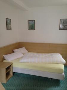 1 dormitorio con 1 cama con sábanas y almohadas blancas en Pension Freund, en Rothenburg ob der Tauber