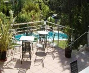 a patio with tables and chairs next to a swimming pool at Hubengut Apartments in Lana