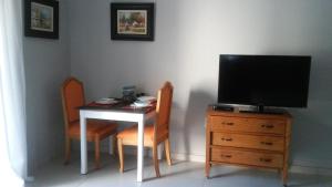 uma mesa com duas cadeiras e uma televisão numa cómoda em @Home Cottage em Joanesburgo