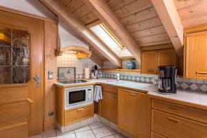 uma cozinha com armários de madeira e um micro-ondas em Ferienhäuser Werdenfels em Mittenwald