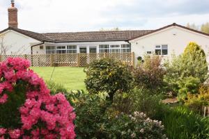 una casa con un jardín con flores rosas en The Stables at Flash Farm House, en Crewe