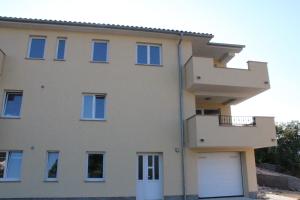 una casa grande con un garaje delante en Apartmani Marin, en Vrbnik