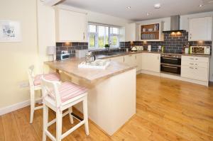a kitchen with white cabinets and a island with two stools at The Stables at Flash Farm House in Crewe
