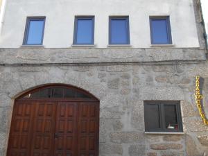 ein Gebäude mit einer Holztür und drei Fenstern in der Unterkunft Coreto Apartments in Sabugueiro