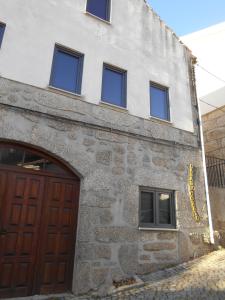 ein Steingebäude mit einer Holztür und mehreren Fenstern in der Unterkunft Coreto Apartments in Sabugueiro