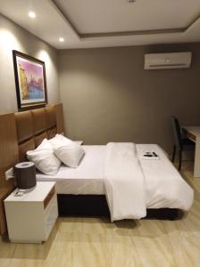 a hotel room with a bed with white sheets and pillows at Blackwood Hotels in Ikeja