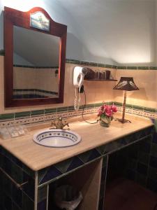 a bathroom with a sink with a lamp and a mirror at Hotel Baviera in Linares