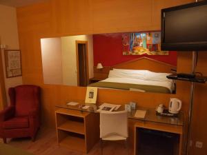 
a hotel room with a bed, desk and television at Platjador in Sitges
